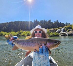 Lady Angler with a nice trout and waterfall in the background.